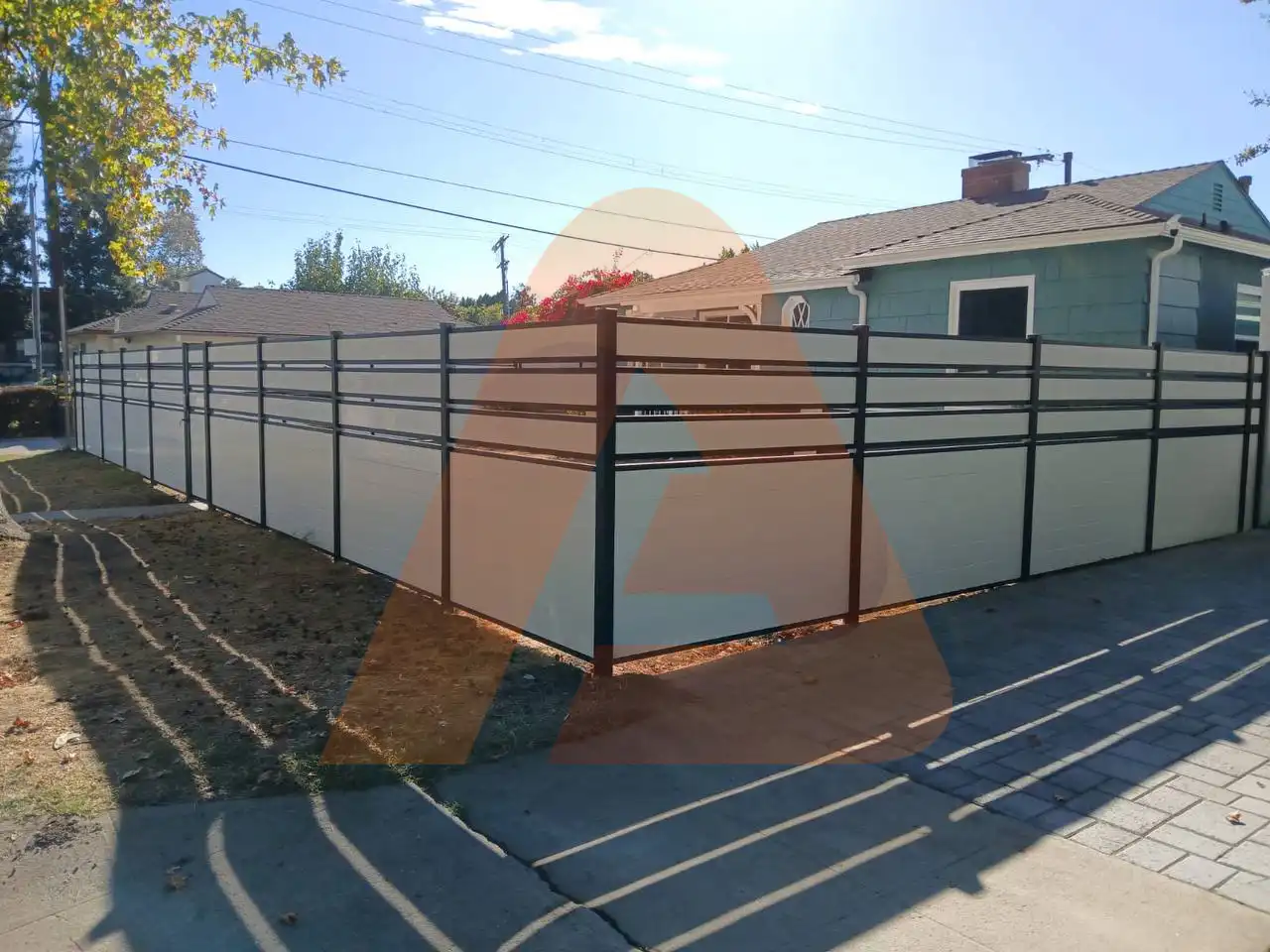 White fence with black posts installed in a residential backyard.