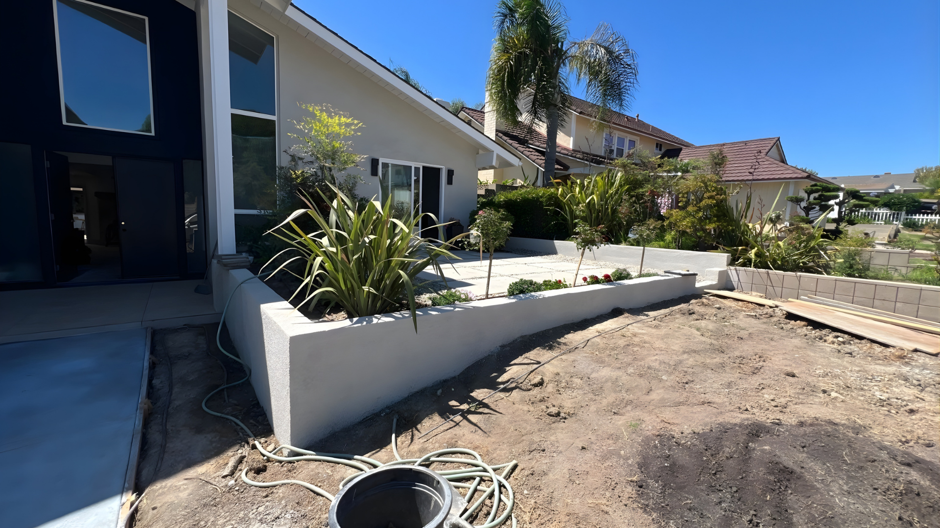 Modern residential front yard with custom concrete boundary wall and landscaped garden area