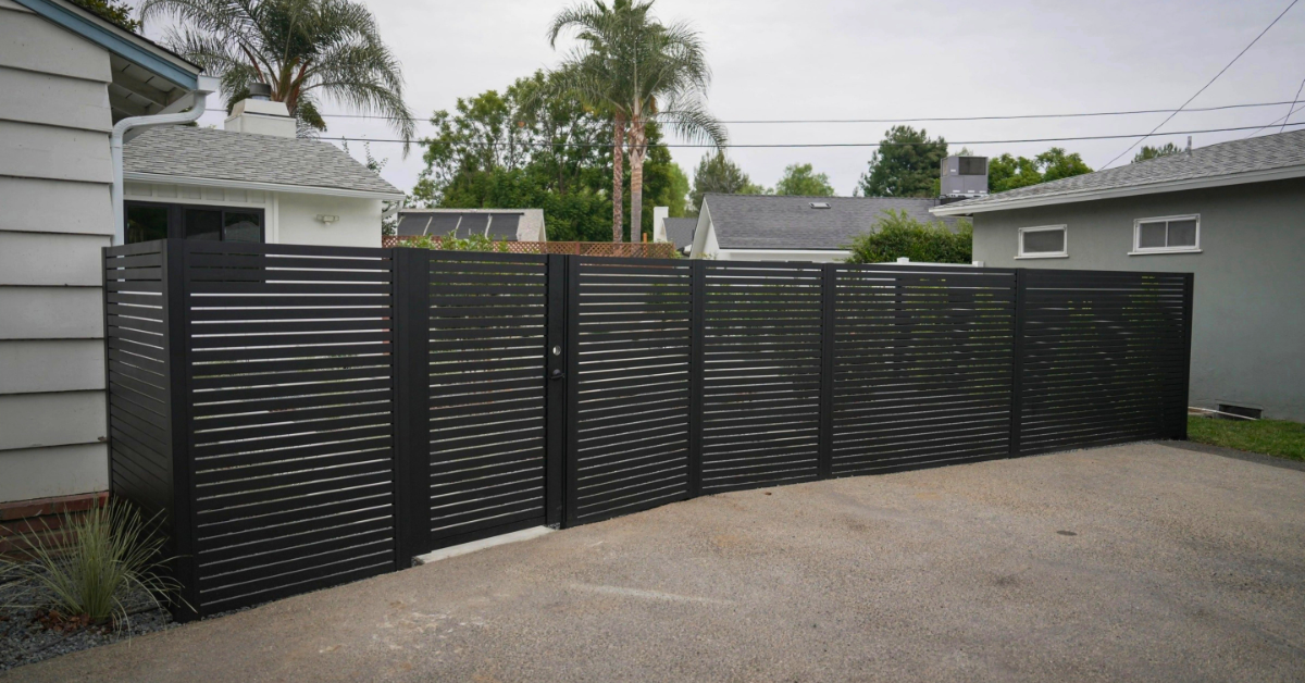Modern black horizontal slat aluminum fence and gate installed in residential driveway for privacy and security