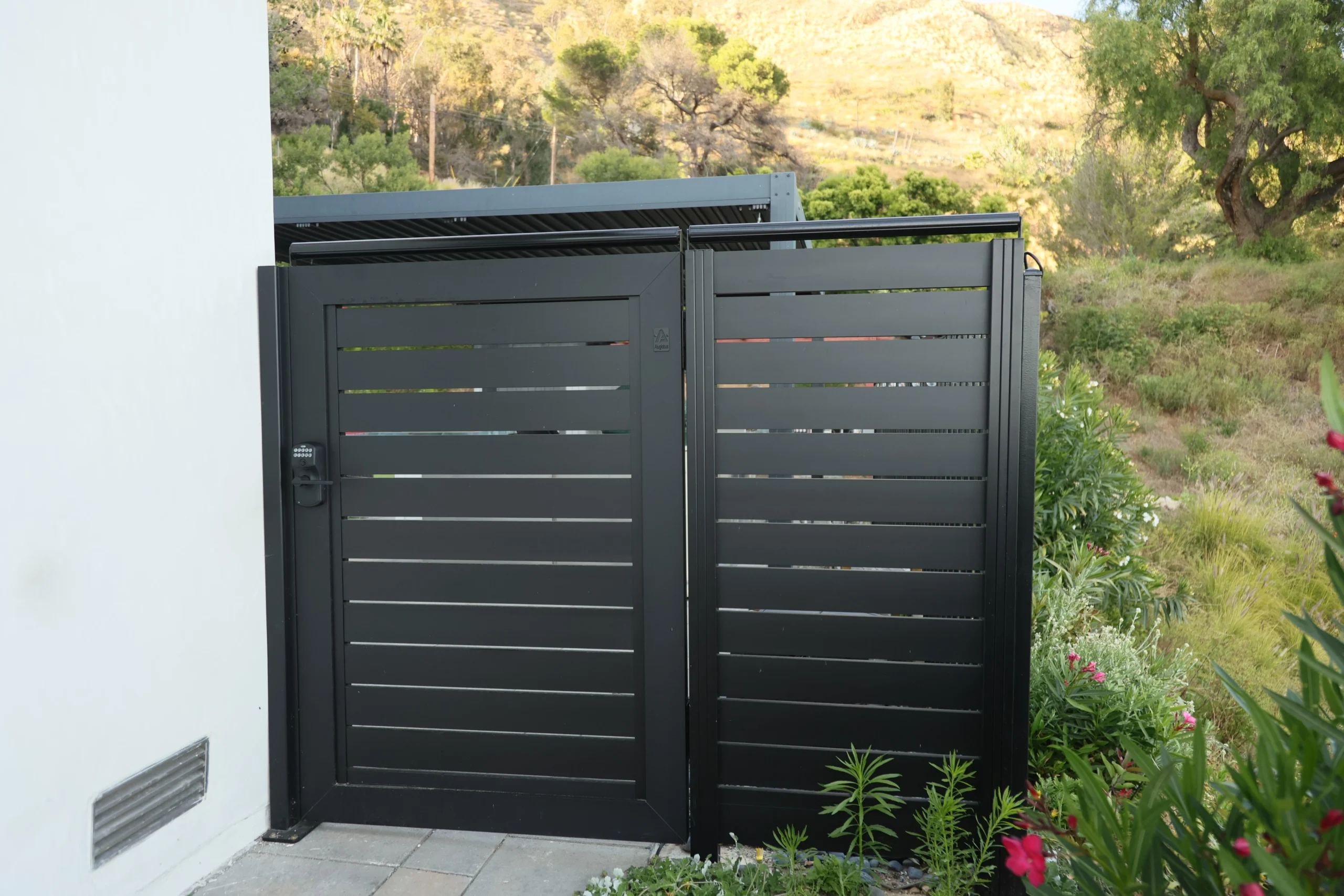 Black aluminum gate with coyote roller system installed on top