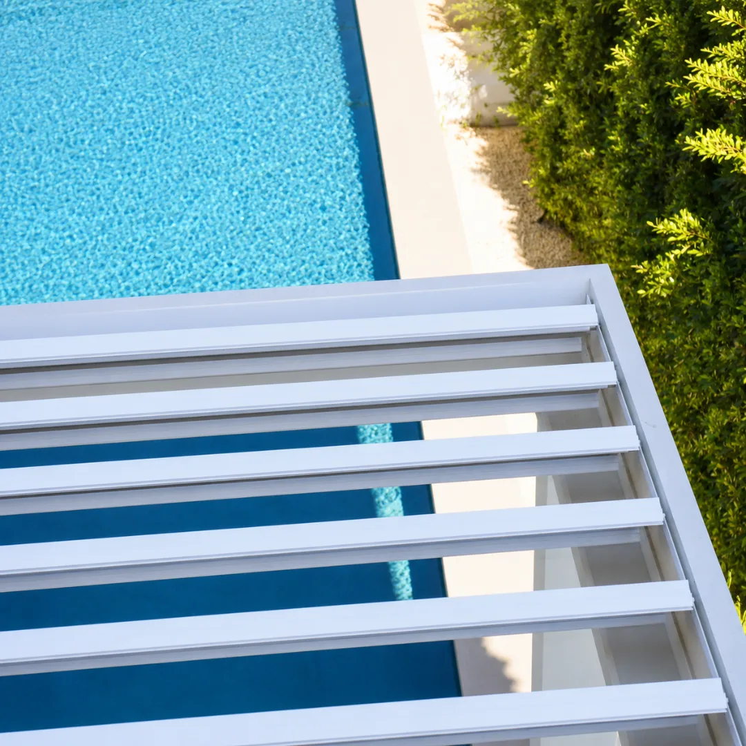 Top view of a white aluminum louver roof frame beside a swimming pool