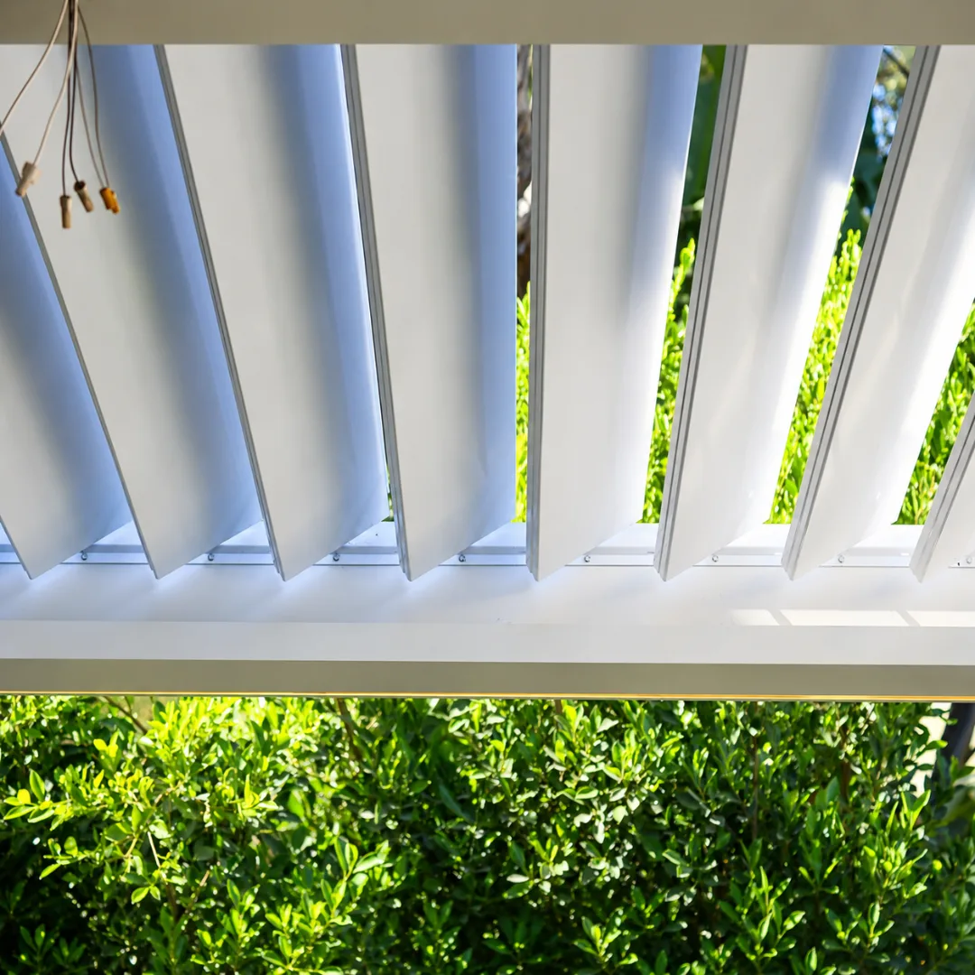 Close-up of white motorized louver blades angled open for ventilation