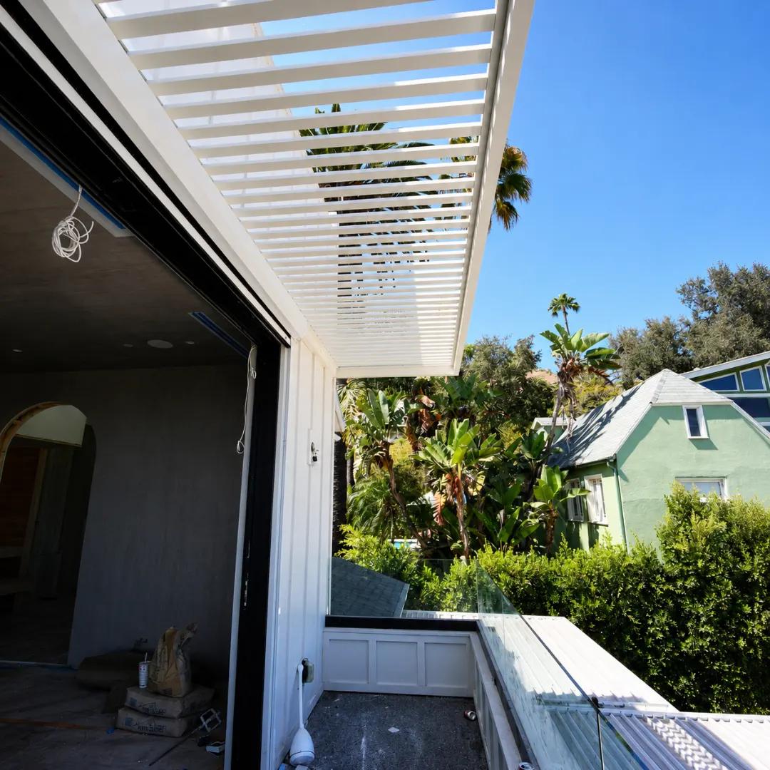 White wall-mounted aluminum louver canopy above an upper-level outdoor area