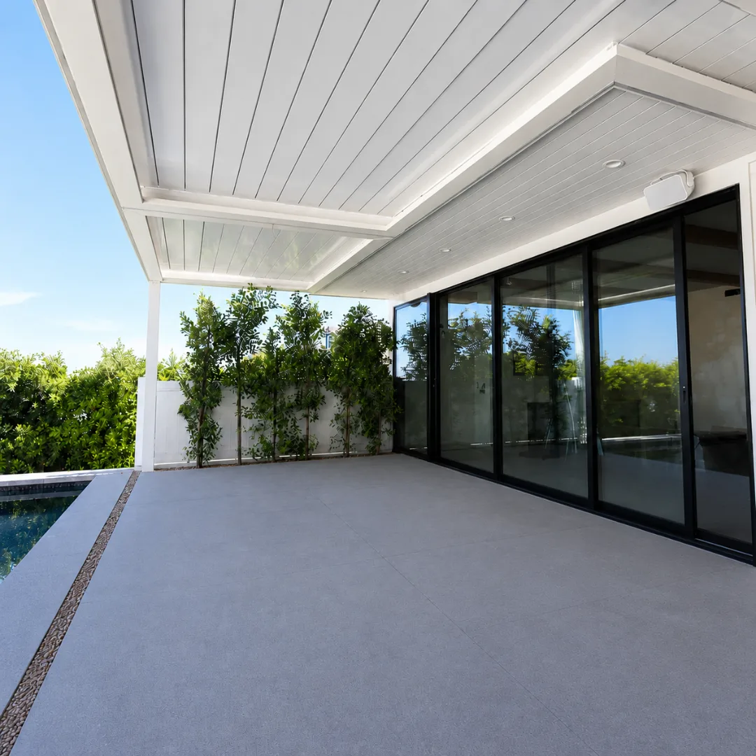 White automatic louver patio cover closed beside a pool and sliding glass doors