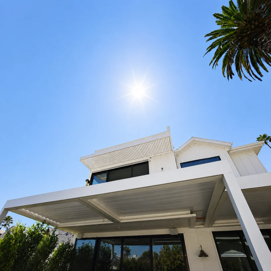 White multi-zone automatic louver patio cover installed below a second-story balcony