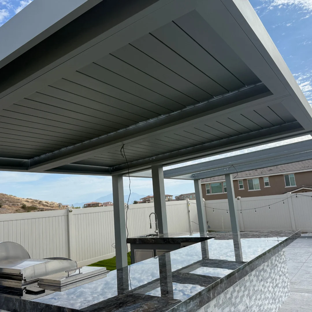 Gray closed motorized louver roof above a custom backyard outdoor kitchen