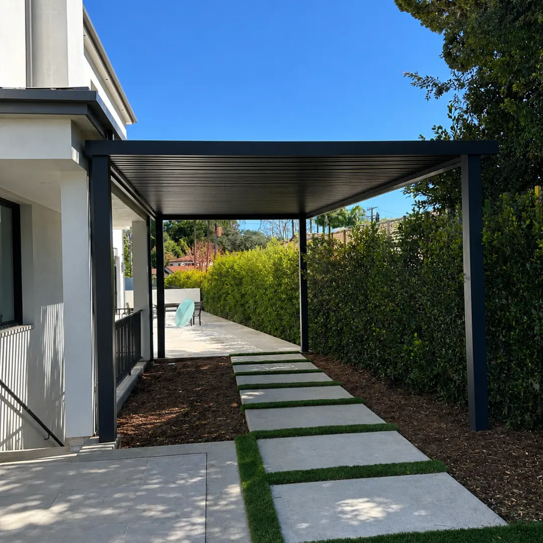 Black aluminum slat patio cover over a side-yard walkway beside a modern home