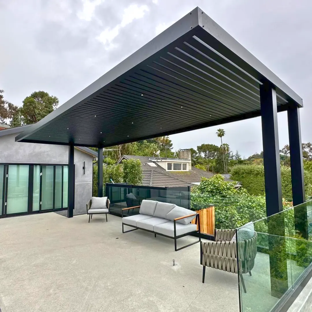Black aluminum slat patio cover with recessed lights above an elevated terrace seating area