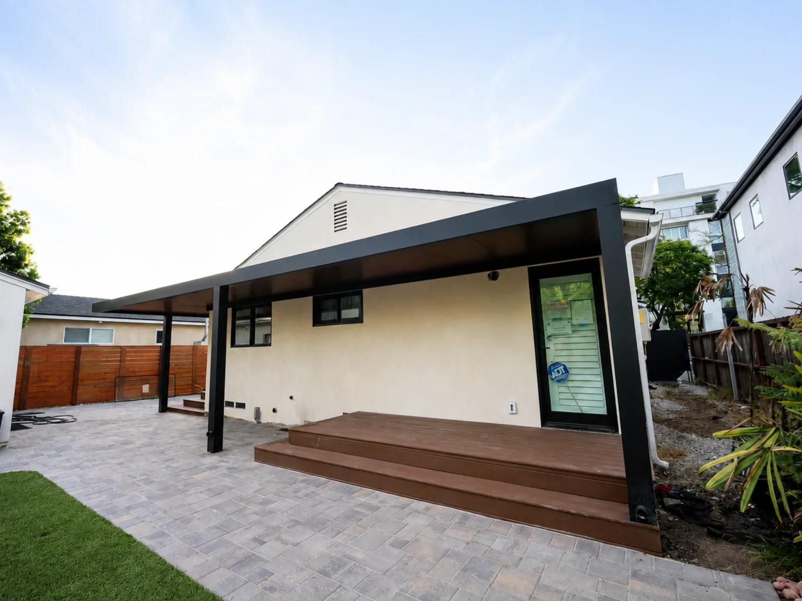 Attached black aluminum patio cover with a wood-look insulated ceiling over a backyard deck