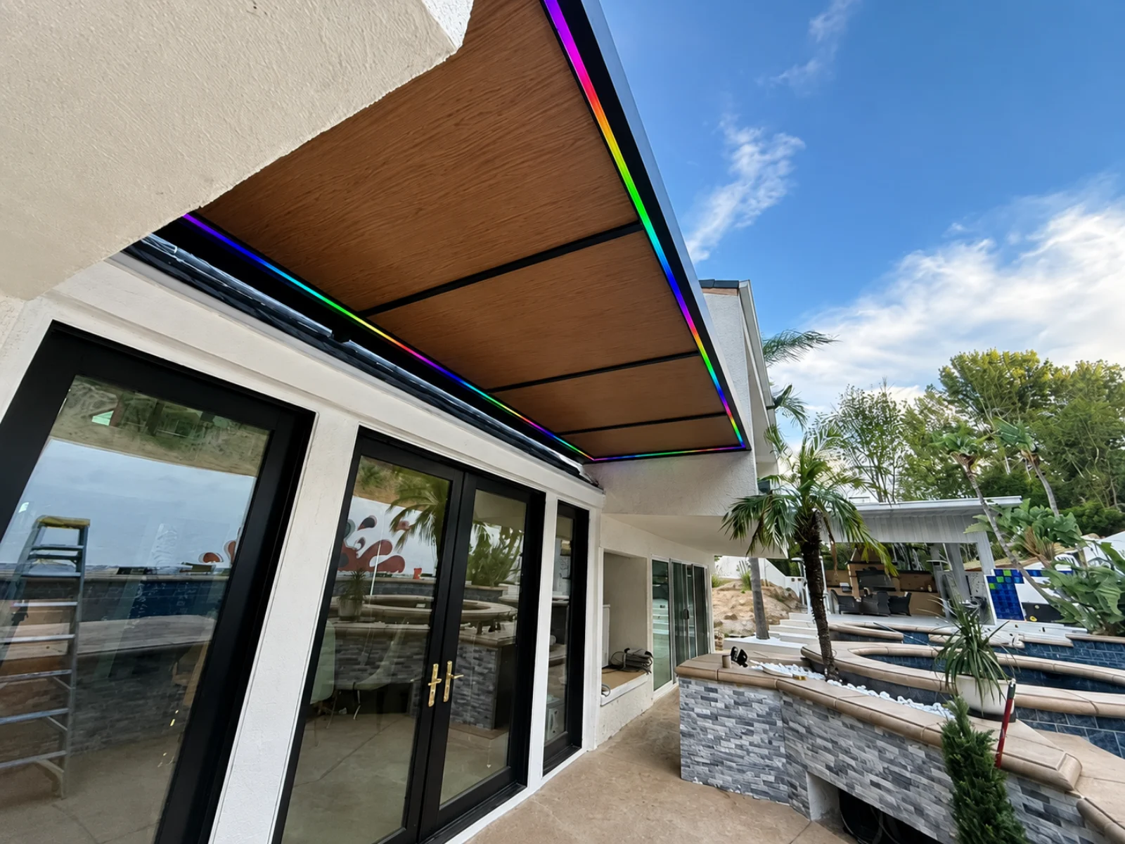 Attached insulated aluminum patio cover with a wood-look ceiling, recessed lights, and perimeter LED lighting