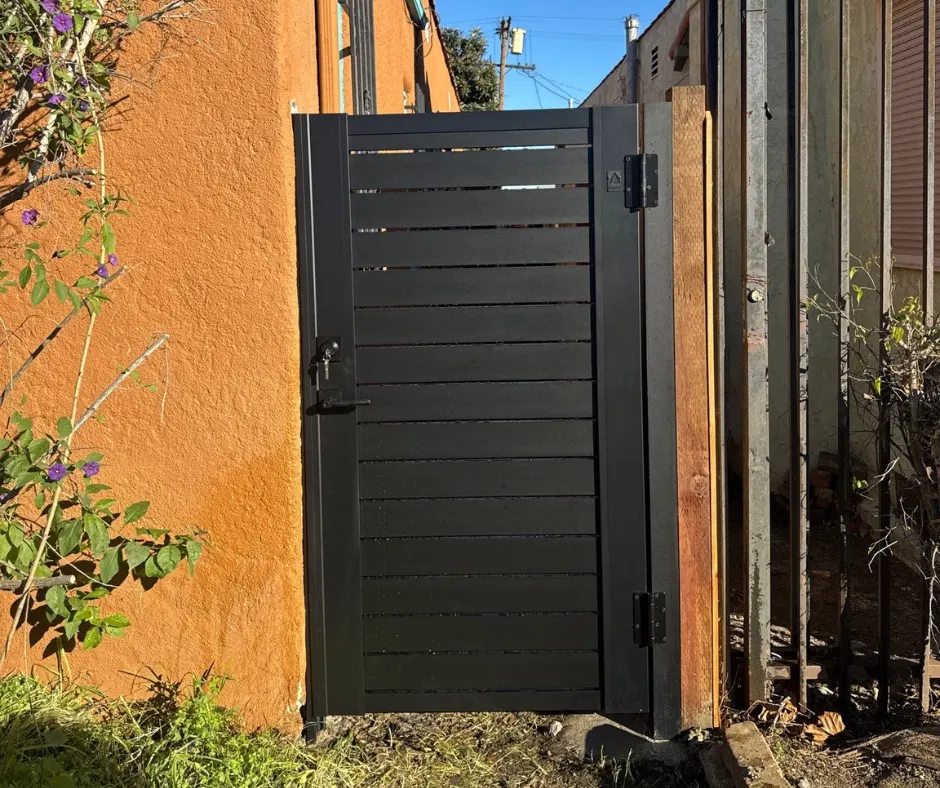 Black pedestrian gate installed in a narrow side passage
