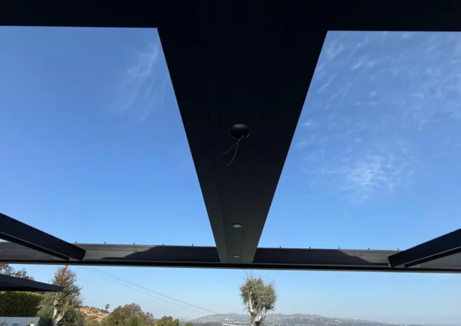 Modern black motorized louvered pergola roof with recessed LED downlights installed above poolside deck