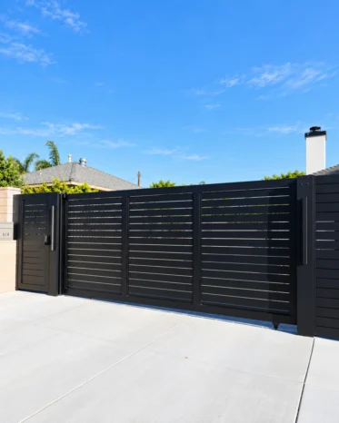 Smooth-sliding motorized horizontal aluminum driveway gate aligned flush with boundary fence panels.