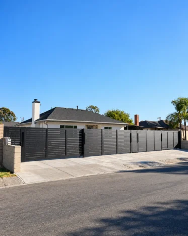 Contemporary black aluminum slat boundary wall framing tropical palm landscaping in Miami.
