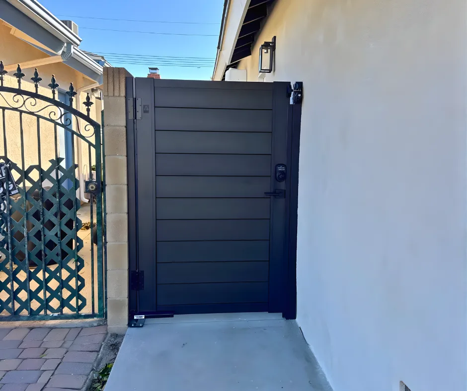Finished black horizontal-slat pedestrian gate beside a house