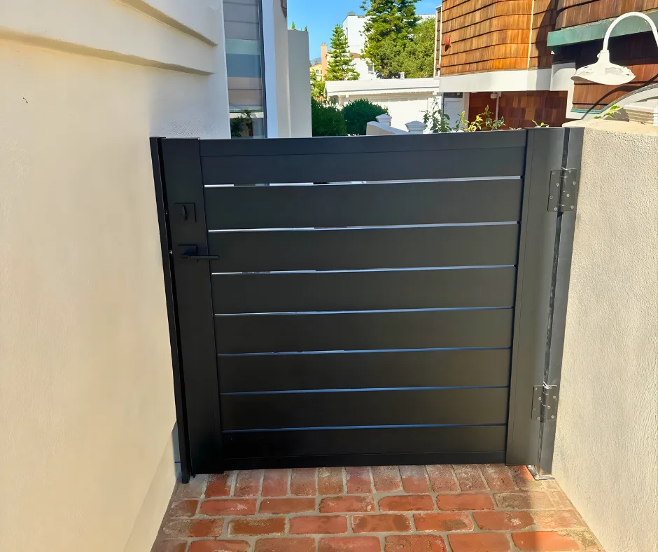 Finished gate installed between wall-mounted supports above a brick walkway