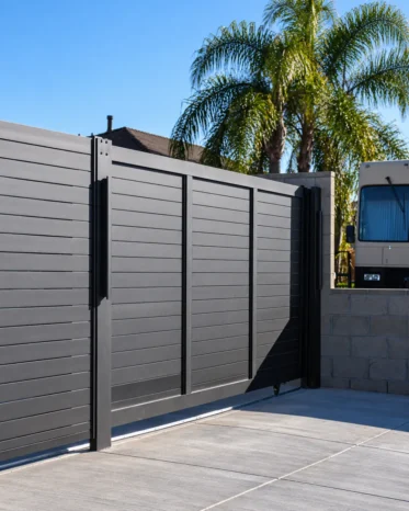 Heavy-duty hinges and keyed security lock hardware mounted on black aluminum pedestrian gate.