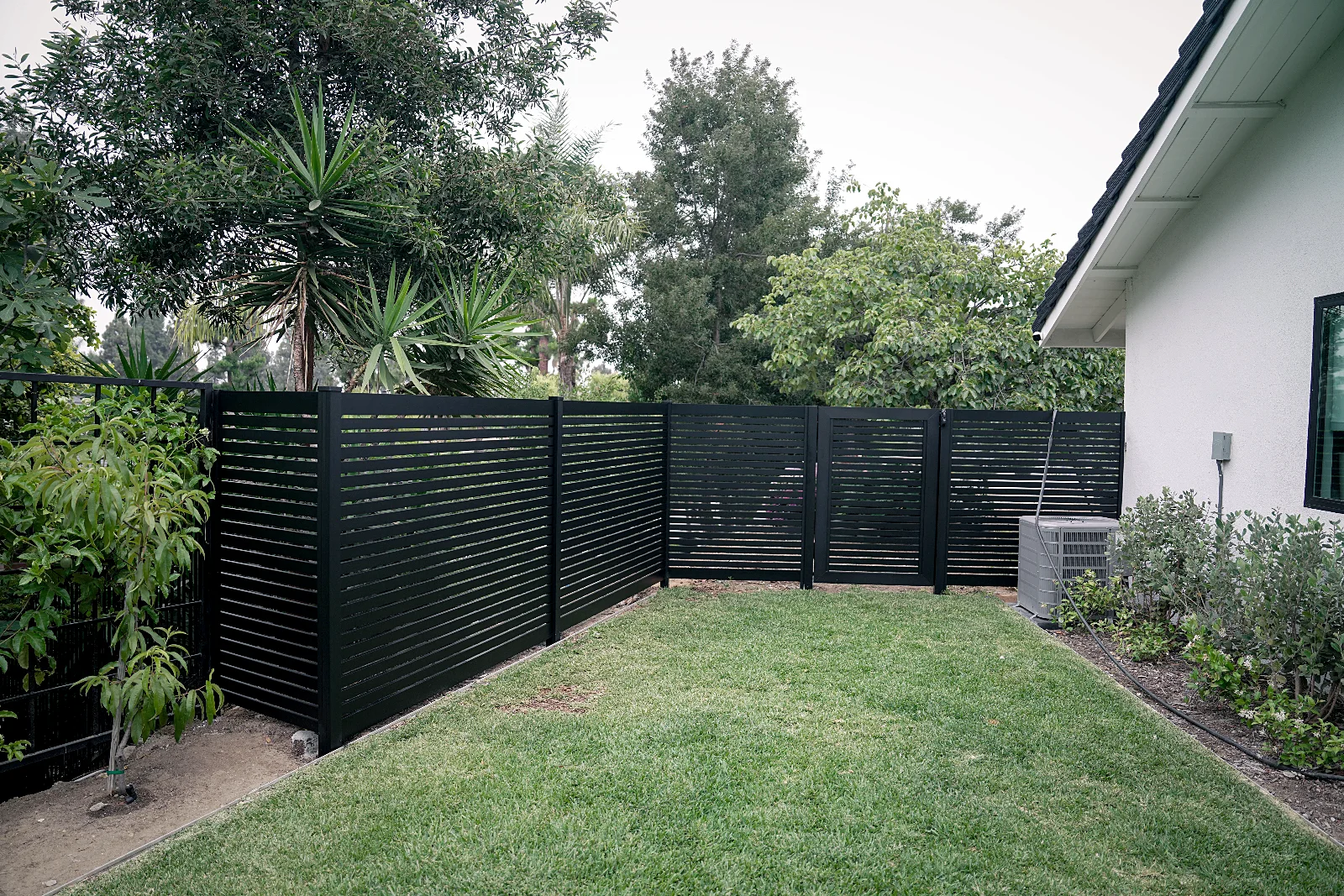 Black ALU20 horizontal slat fence around a backyard lawn