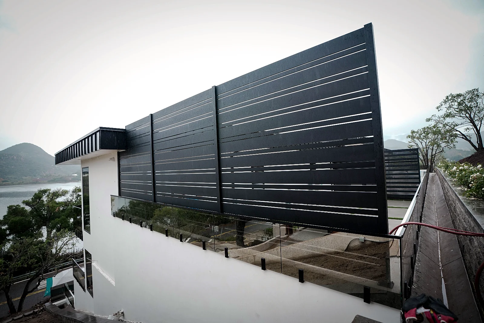 Tall black ALU20 privacy screen beside a white house