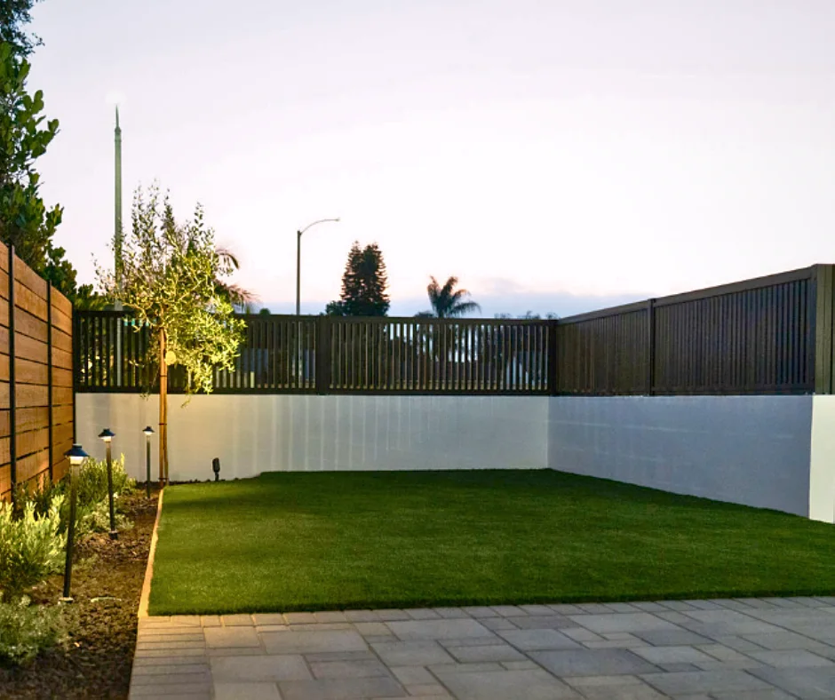 Black ALU20 fence on a white wall around a lawn