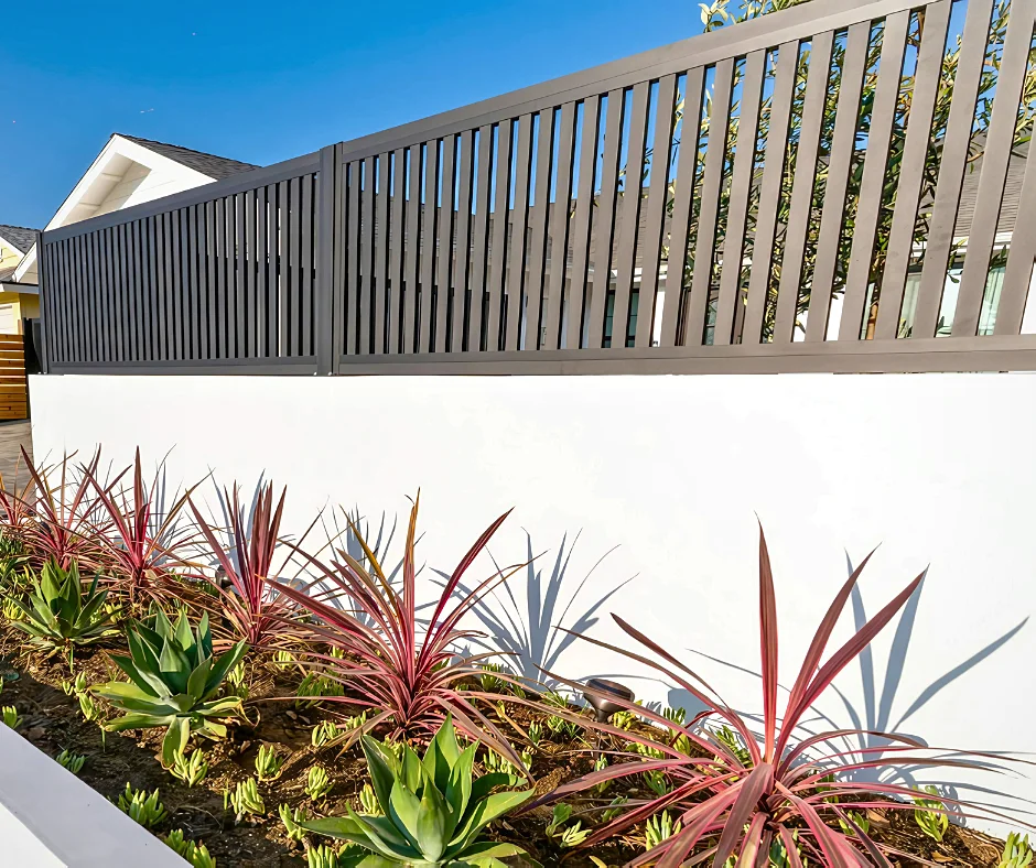 Vertical slat aluminum fence over a garden wall