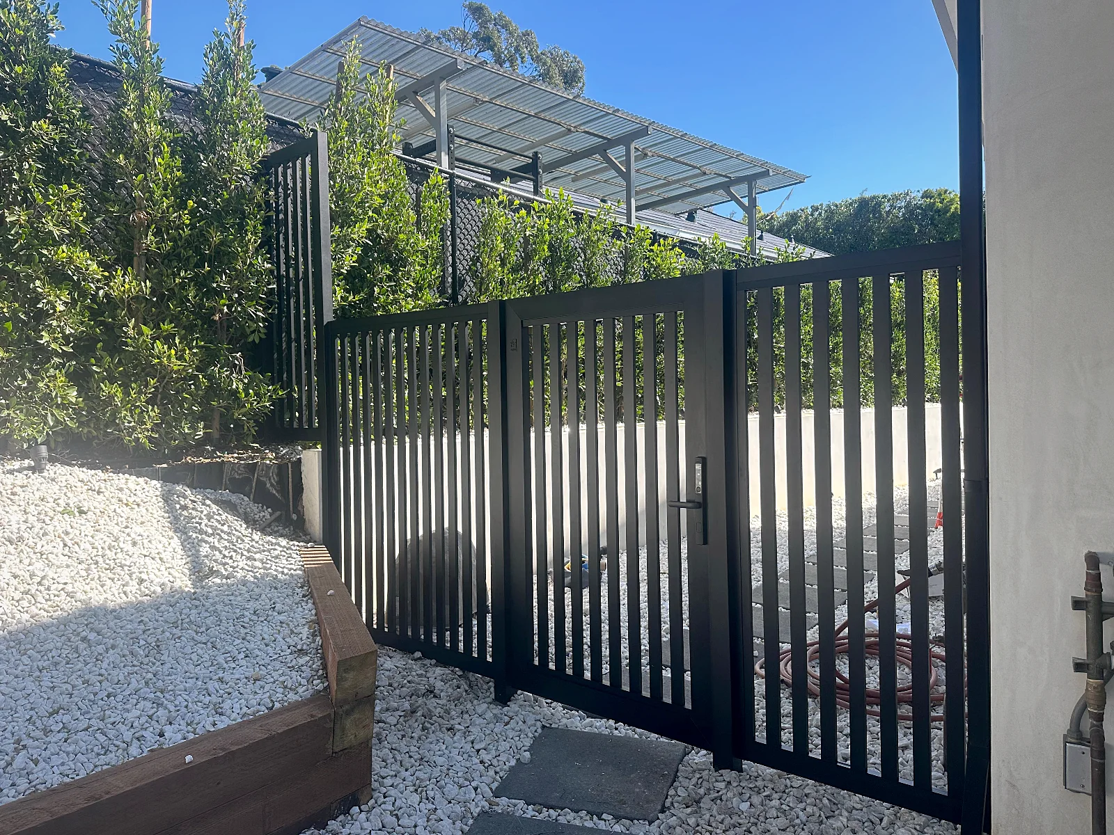 ALU20 vertical slat black gate in a gravel side yard