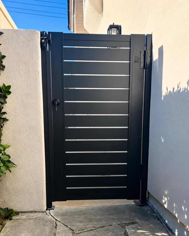 ALU 40 black slat side-yard gate with keyed latch between stucco walls