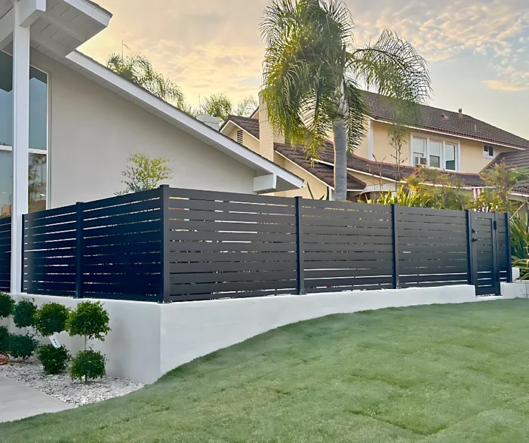 Black ALU40 fence on a white wall above a lawn