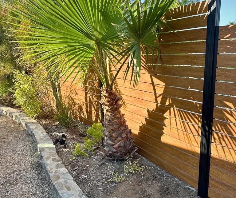 Wood grain ALU40 fence with black posts beside a palm