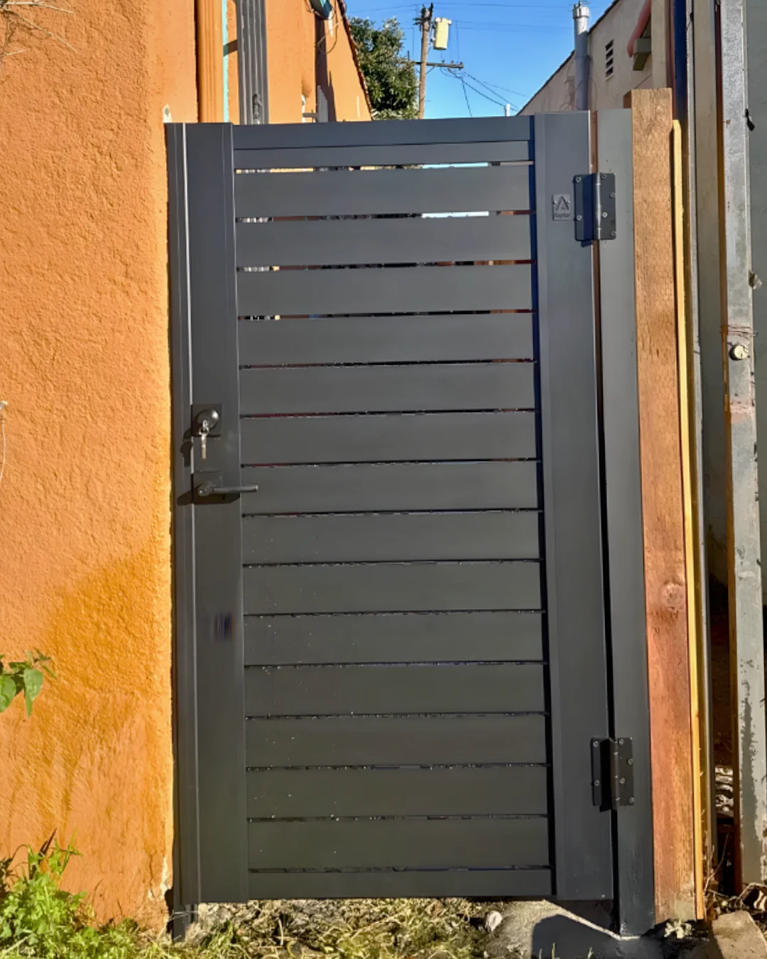 ALU40 black gate against orange stucco