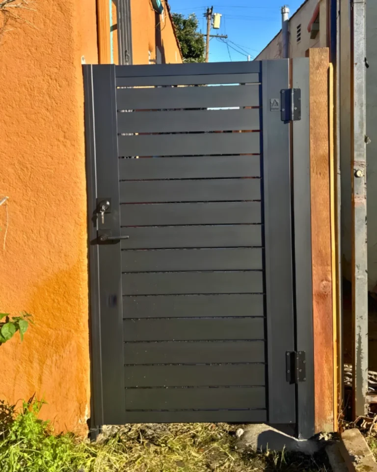 ALU 40 slat pedestrian gate hung beside a stucco wall and wood post