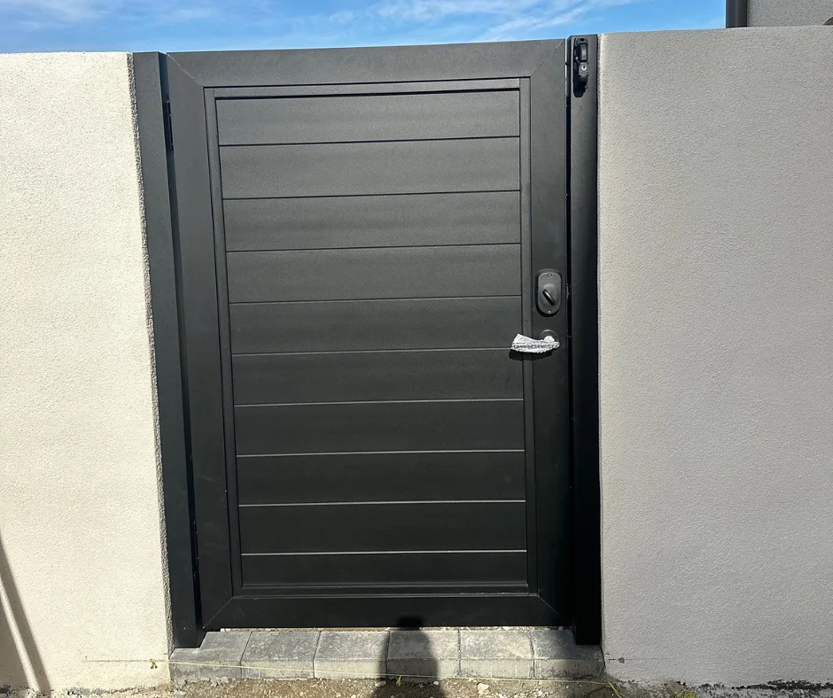 Black ALU60 T&G gate between stucco walls