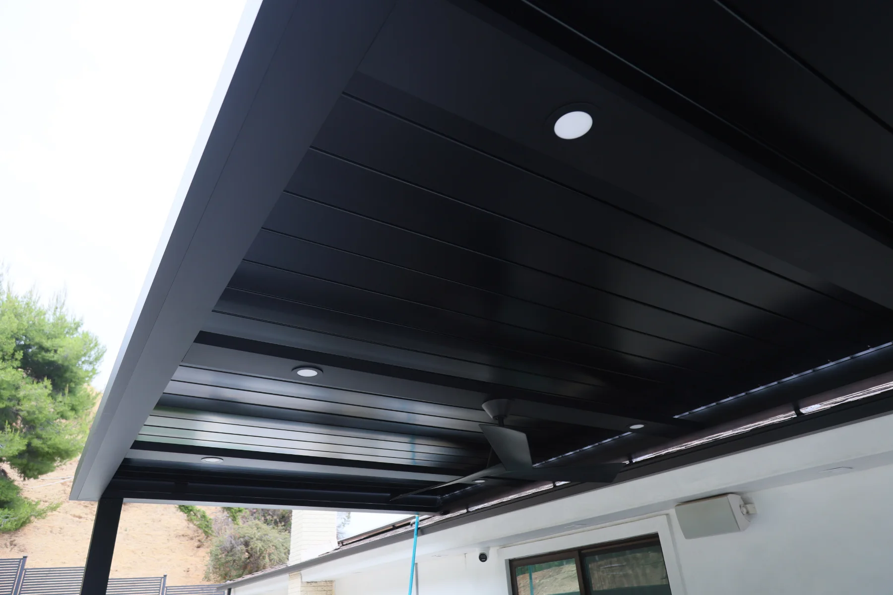 Underside of a black louvered roof with recessed lighting