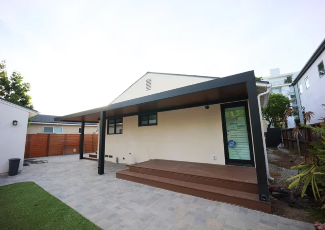 L-shaped insulated aluminum patio roof system sheltering residential back entrance and raised deck stairs.